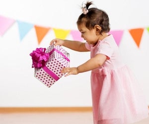 picture of a baby with a wrapped birthday gift photo by canva